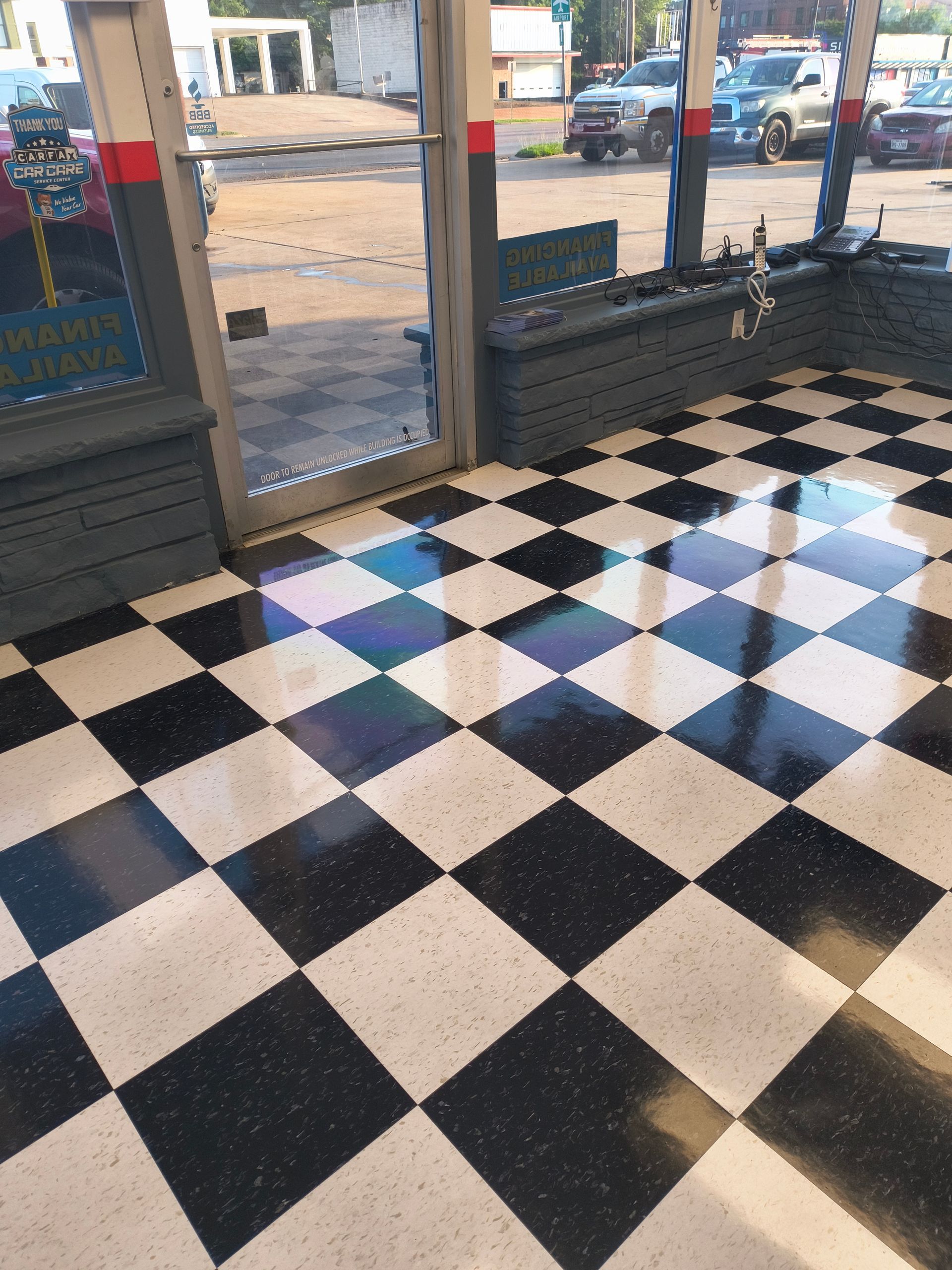 Black and white checkered floor inside a building with a glass door, leading outside to a street.