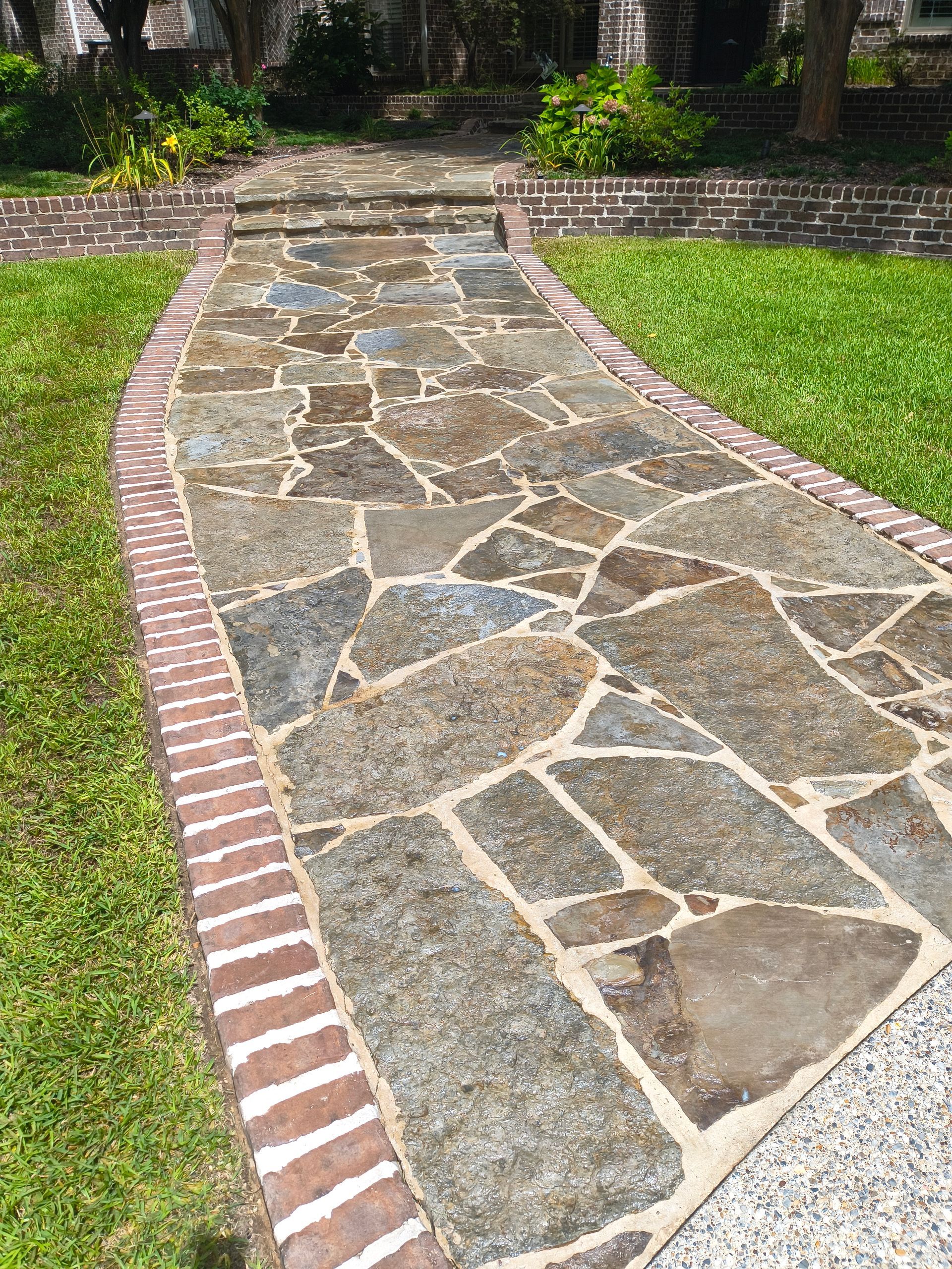 Flagstone pathway with brick edging and green grass.