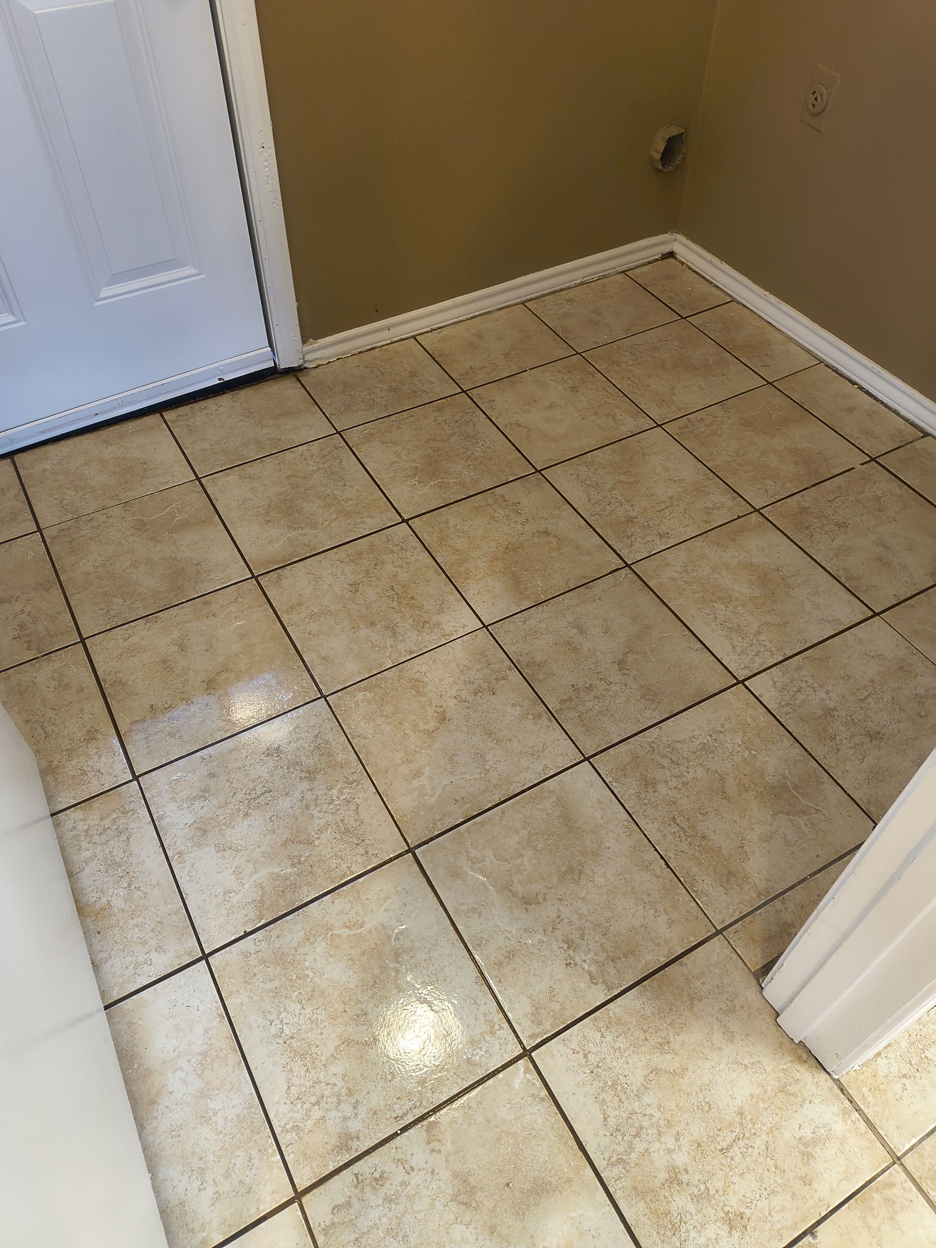 Tan tile floor in room with beige walls and a white door.