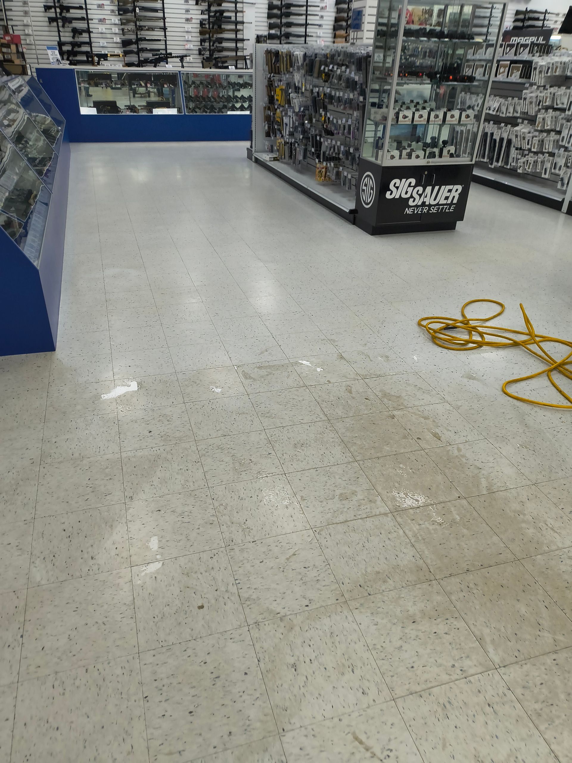 Interior of a store with display cases, a tiled floor, and a yellow extension cord.