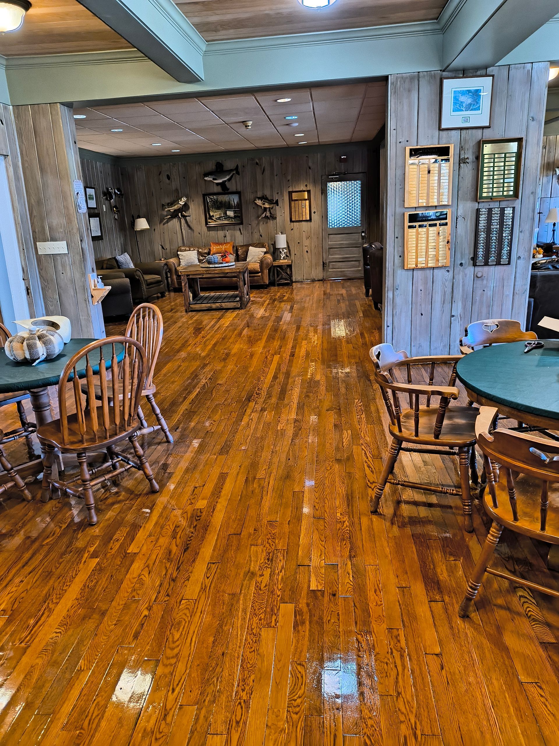 Wooden floored restaurant interior with tables, chairs, and a seating area with artwork.