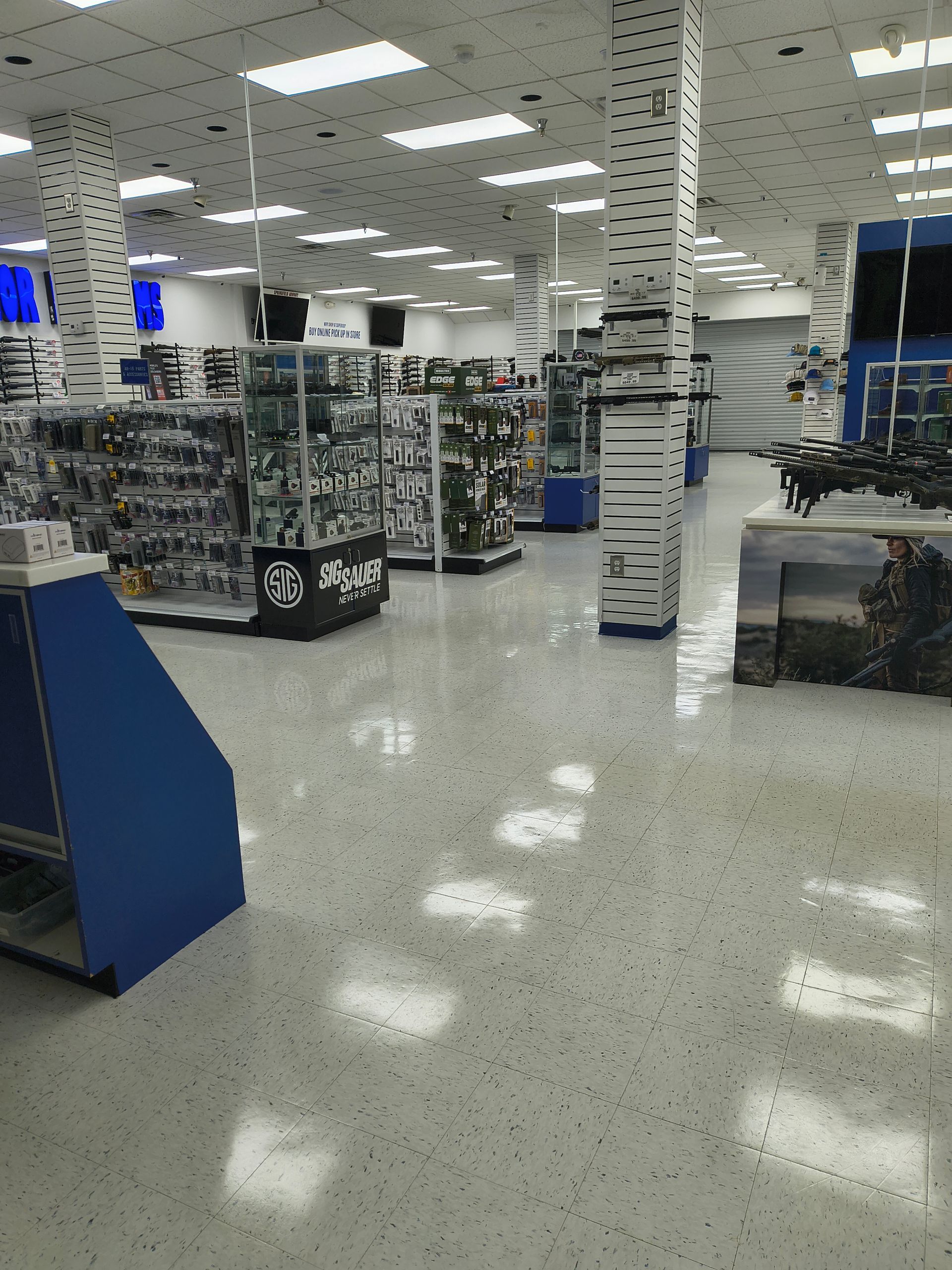 Interior of a large store with white floors and blue accents, showcasing various merchandise displays.