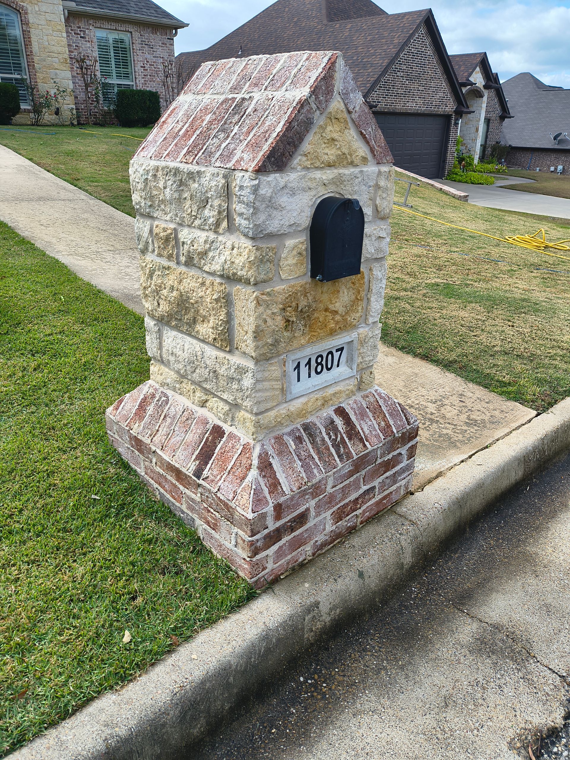 Stone mailbox with address 11837 on a sidewalk.