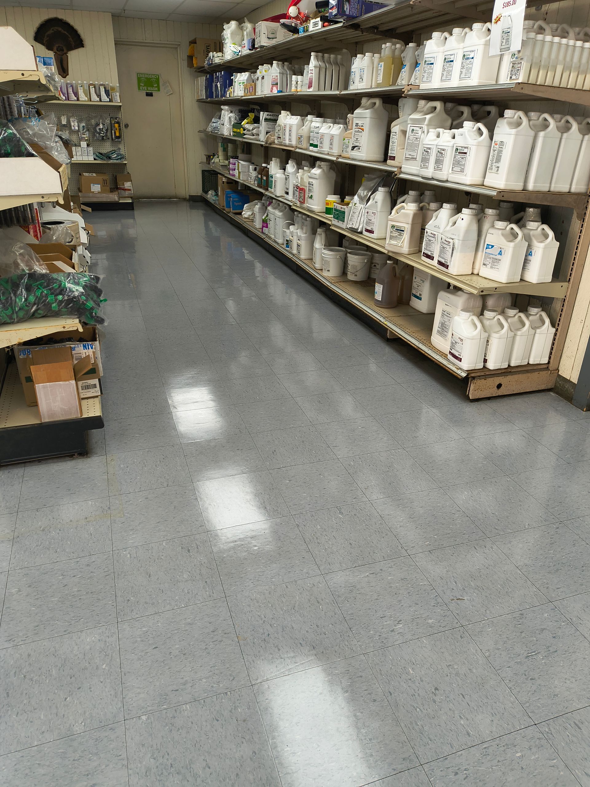 A store aisle with shelves stocked with white bottles and a gray floor.