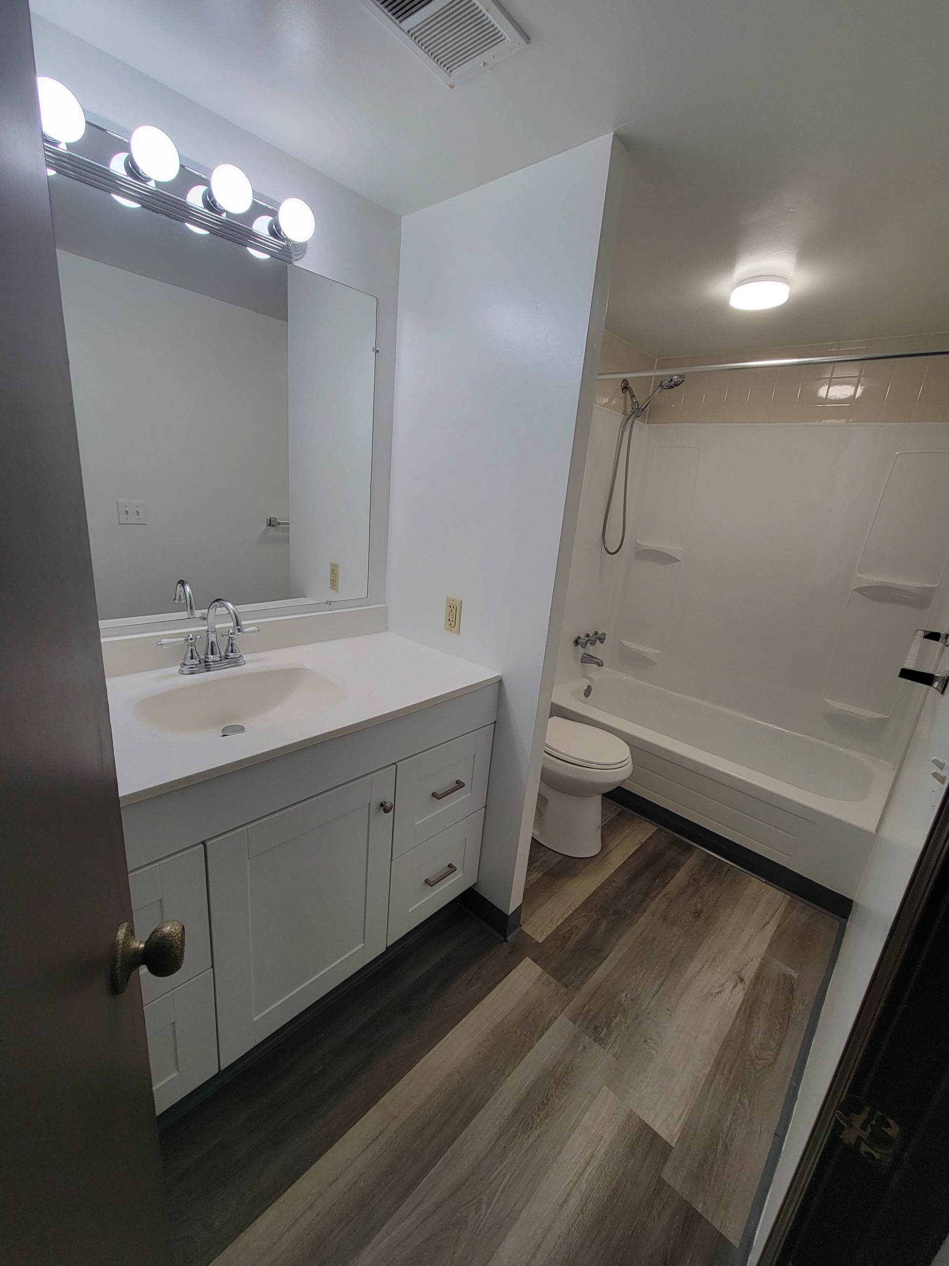 A bathroom with a sink , toilet , tub and mirror.