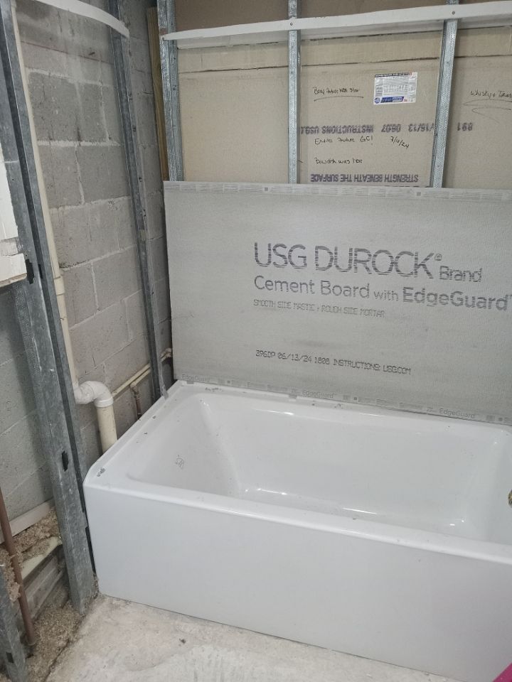 Bathtub installed with Durock cement board in a bathroom under construction.