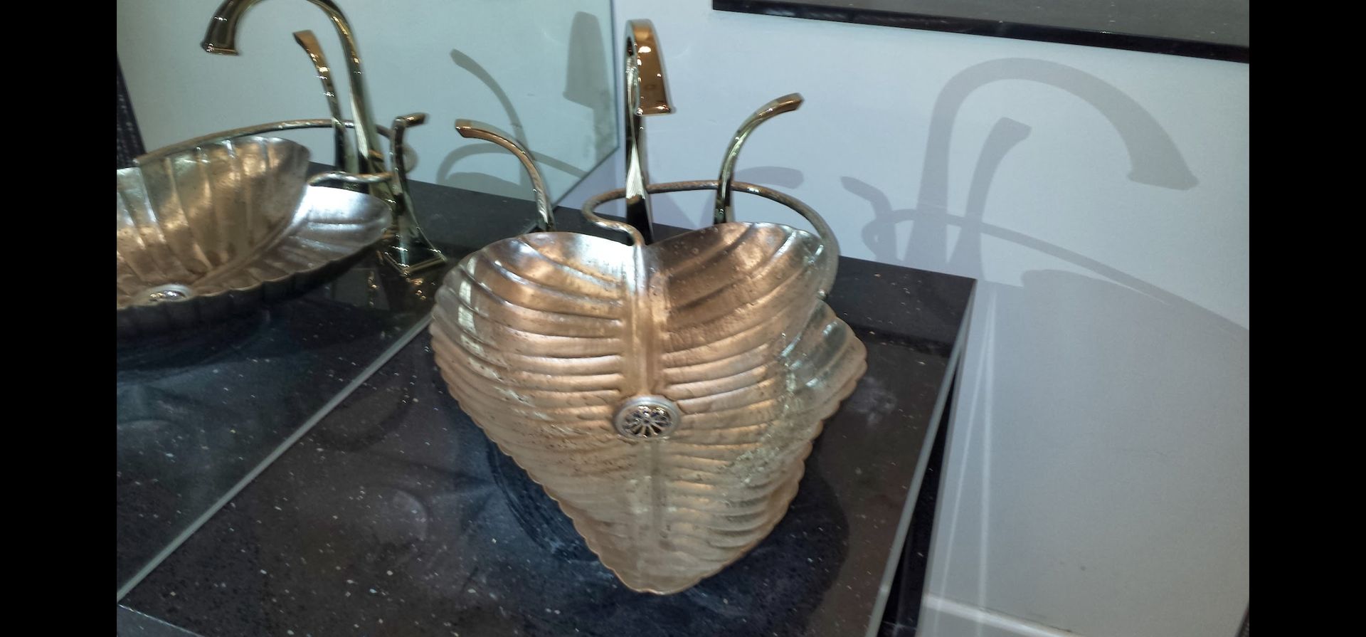 Two ornate gold sinks with swan-shaped faucets sit on a dark countertop.