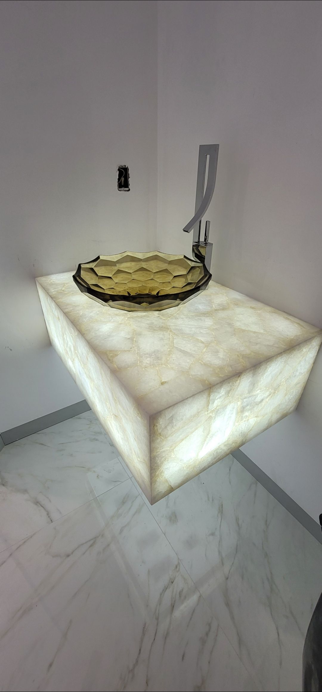 Illuminated bathroom countertop with a circular object on top.