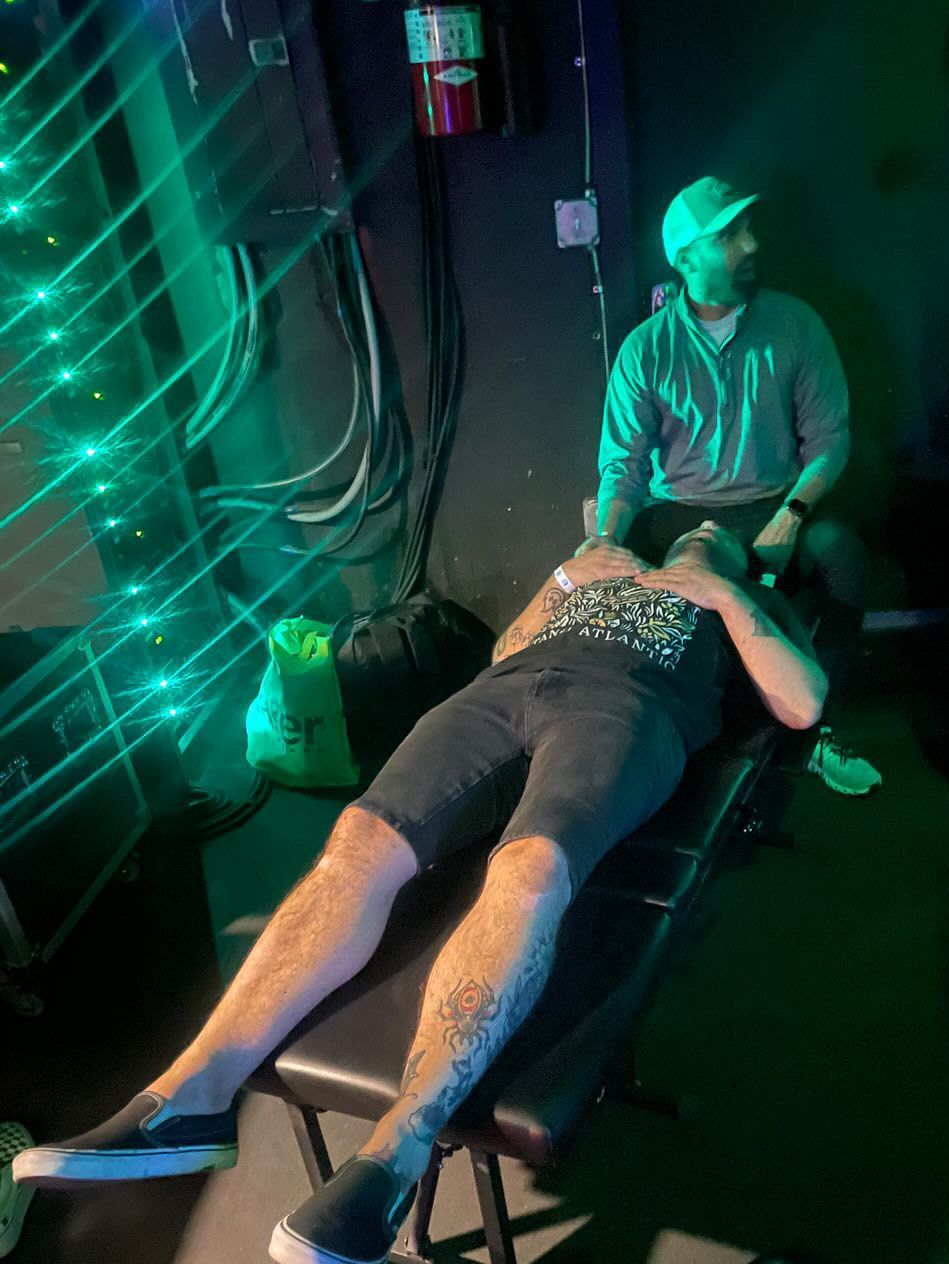 Mike, the tour manager for the band Point North getting his neck adjusted by Dr. Neal Surani backstage.