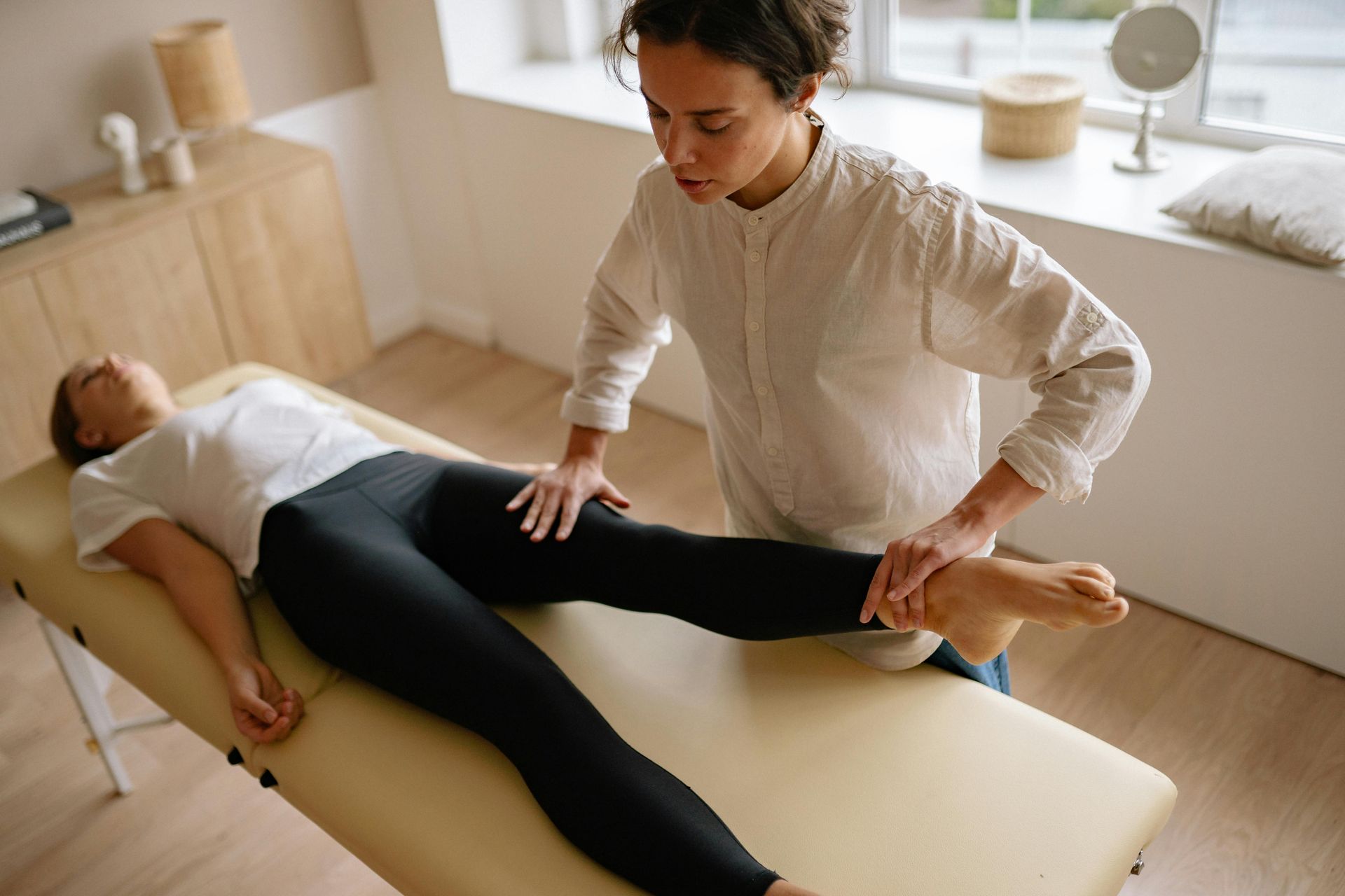 Physical Therapist at Raise Chiropractic in Littleton, CO stretching patient's leg on a therapy table indoors.