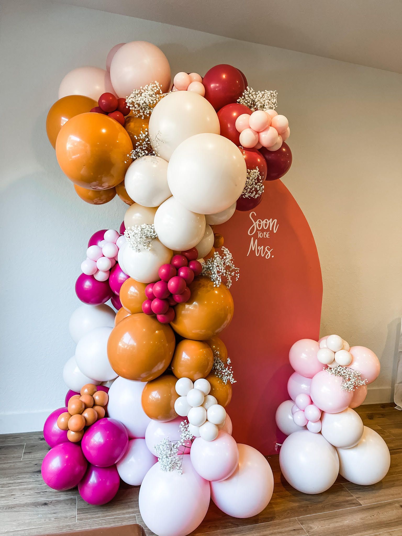 A bunch of balloons are stacked on top of each other on a wooden floor.