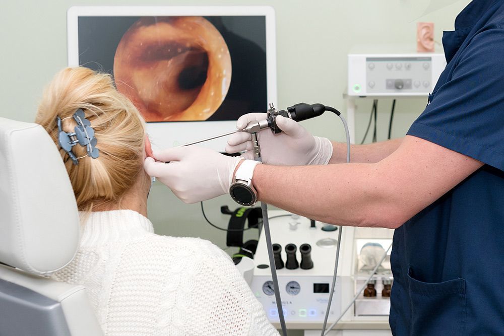 A Doctor Examines a Patient's Ear Canal with An Otoscope — Simply Clear Ear Care in Tea Gardens, NSW 