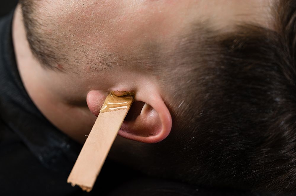 Man Having Ear Hair Waxed with A Wooden Applicator — Simply Clear Ear Care in Tinonee, NSW 