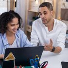 Man and woman discussing in front of an open laptop