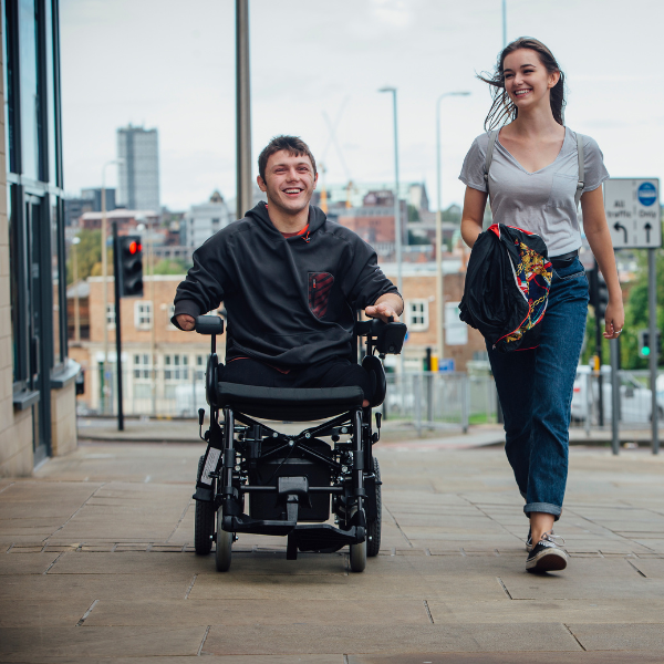 Woman walking together with a man in a wheelchair