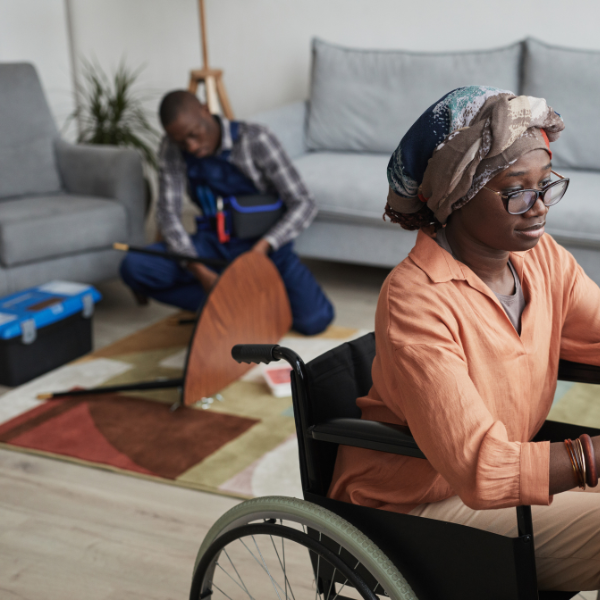 Woman in wheelchair and a man behind her assembling furniture