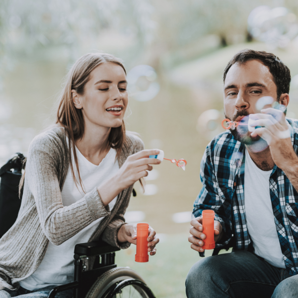 Man and woman in wheelchairs blowing bubbles