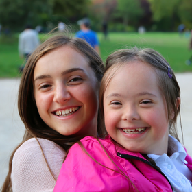 Woman carrying young girl with disability