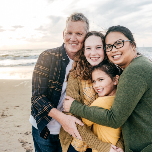 Multicultural family hugging together at the beach
