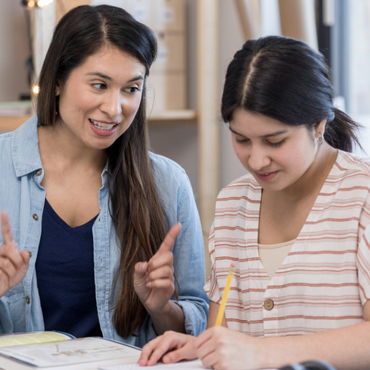 Two women talking, one woman holding pen and paper