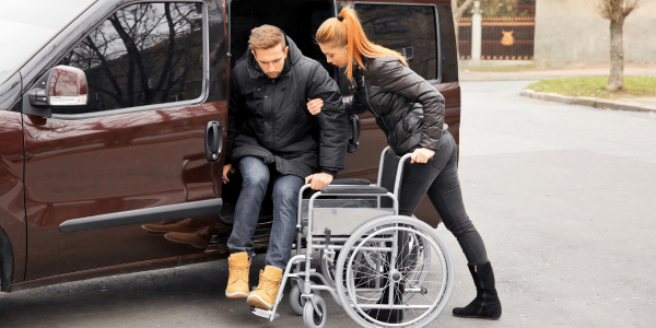 Woman helping man from car to a wheelchair