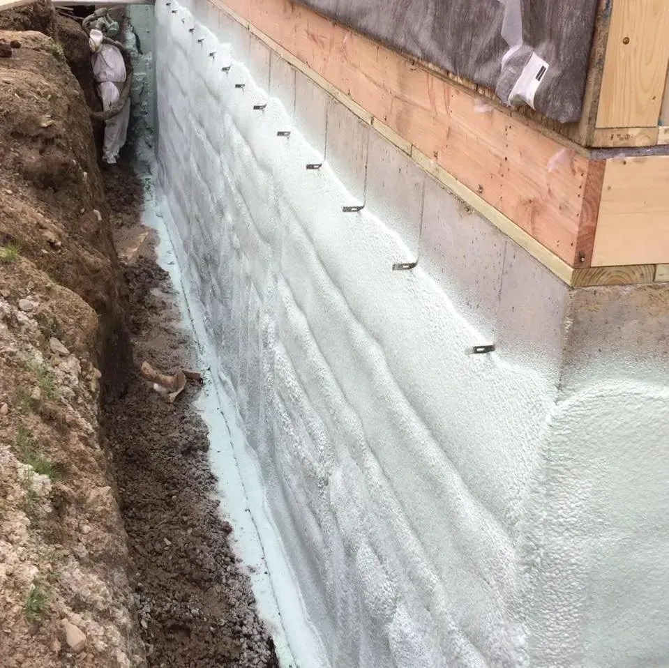 A foundation of a house is being waterproofed with foam.