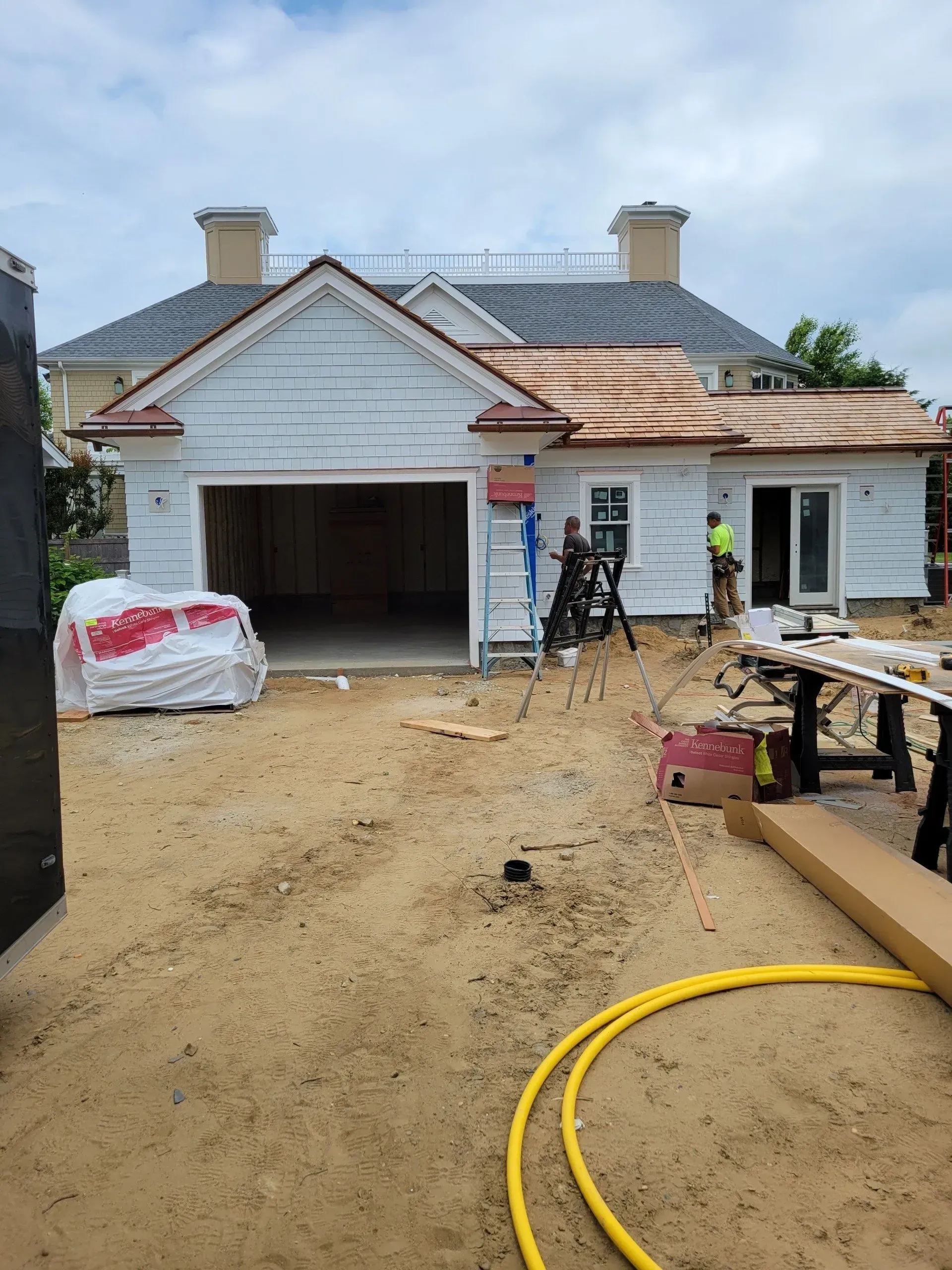 A large white house is being built with a copper roof.