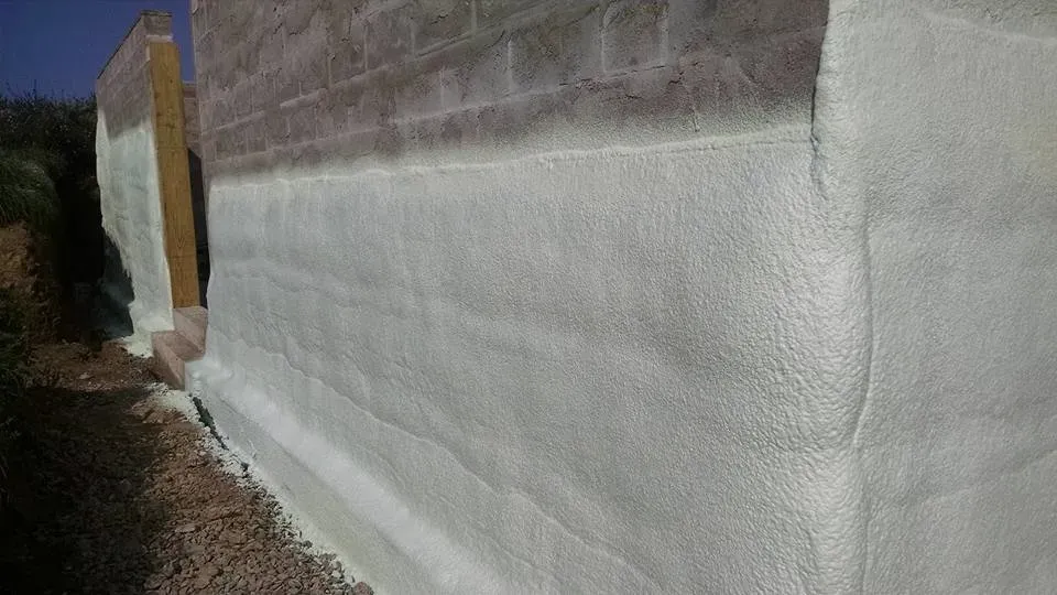 A brick wall is covered in white spray foam.