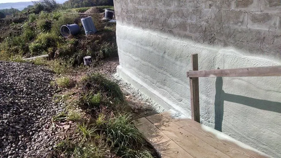 A wooden bench is sitting next to a brick wall.