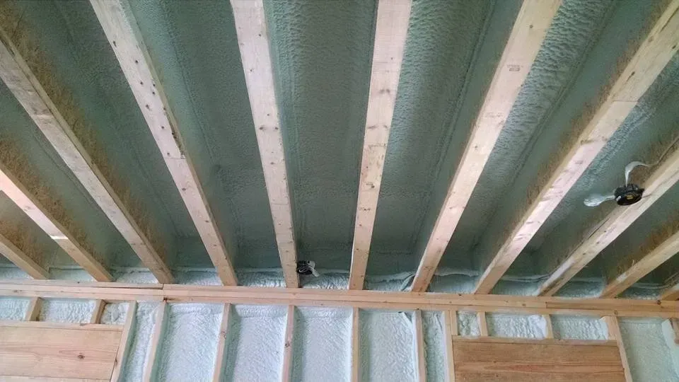 The ceiling of a house under construction with wooden beams and insulation.