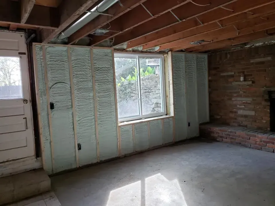 A basement with a window and a brick fireplace.
