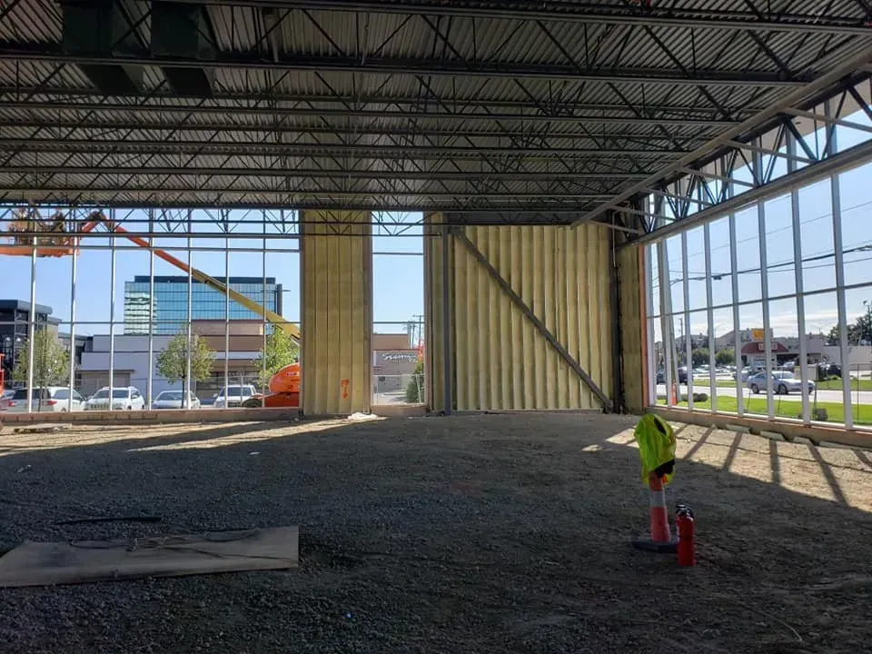 A man in a yellow shirt is standing in an empty building under construction.