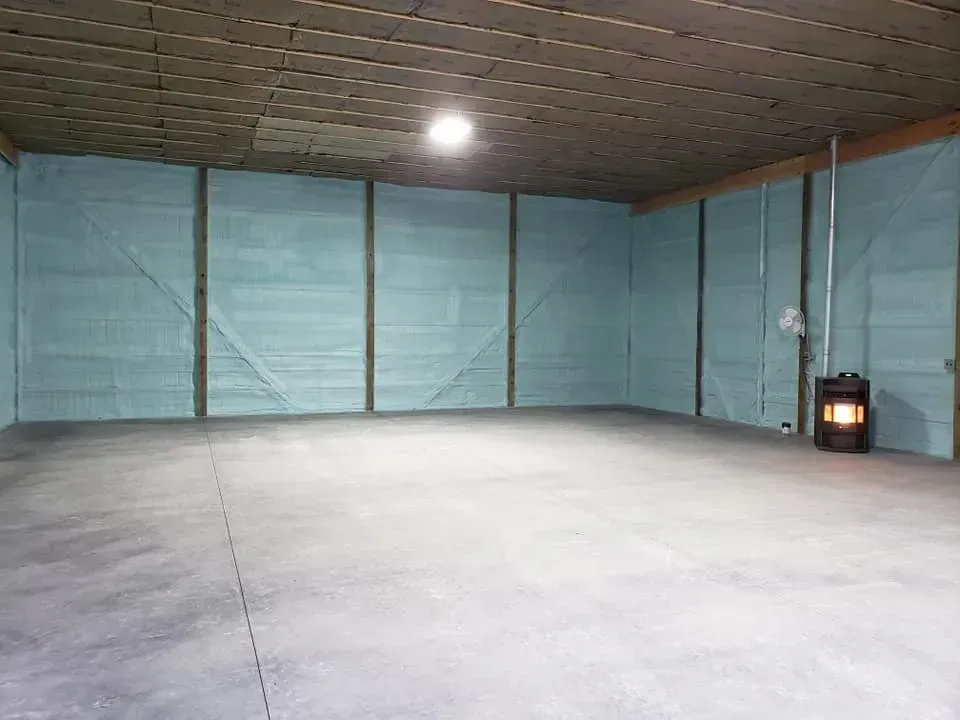 A large empty garage with a heater in the corner.