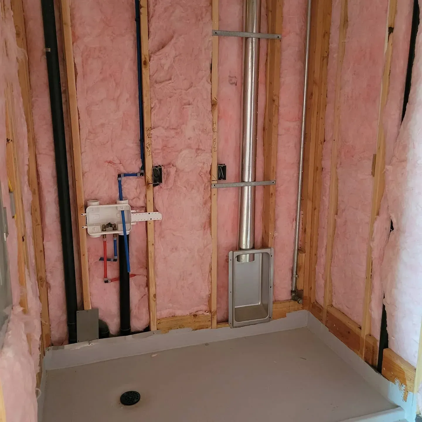 A bathroom with pink insulation and a shower stall