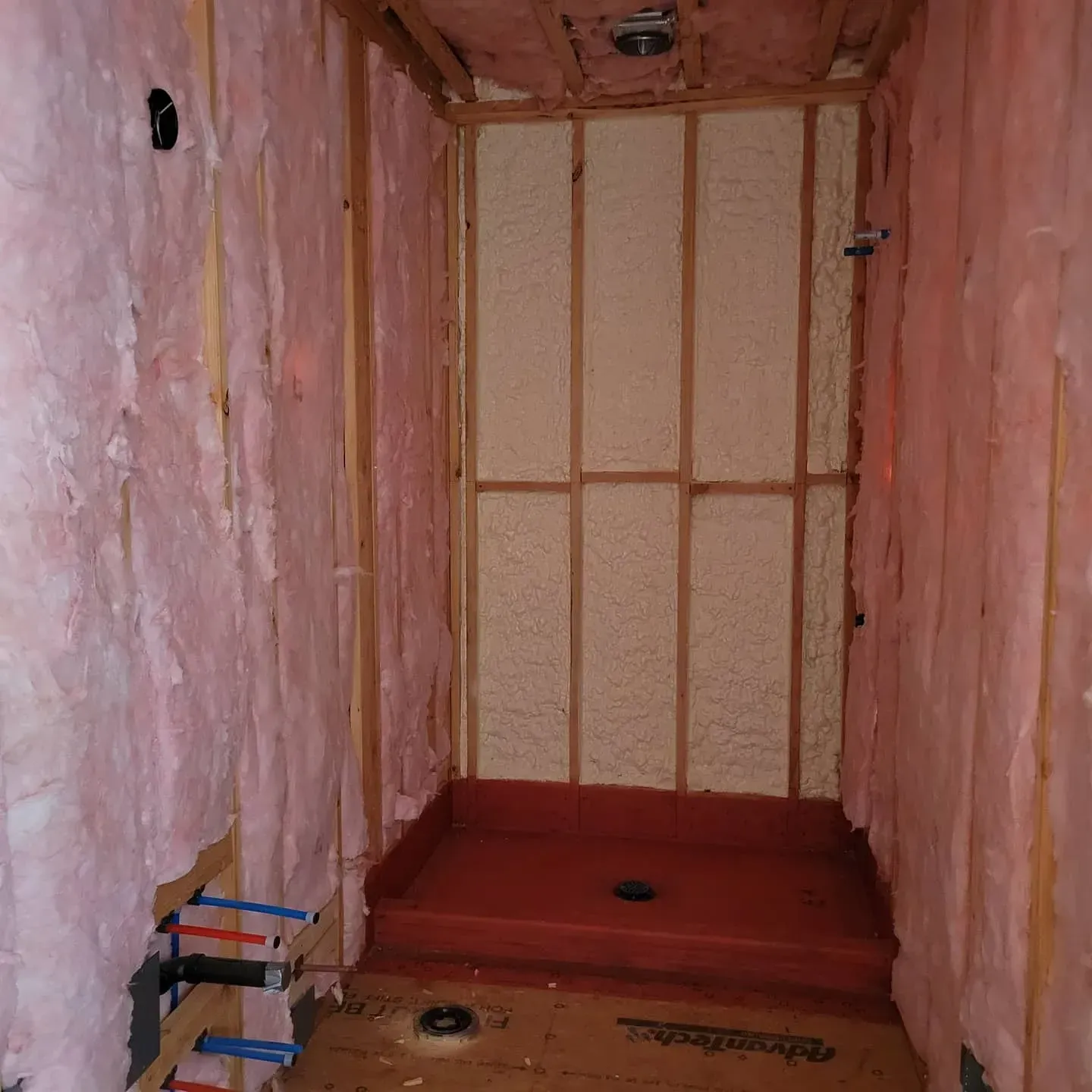 A room with pink insulation on the walls and a red floor.