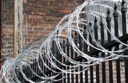 Barbed wire looped around the top of a black steel security fence