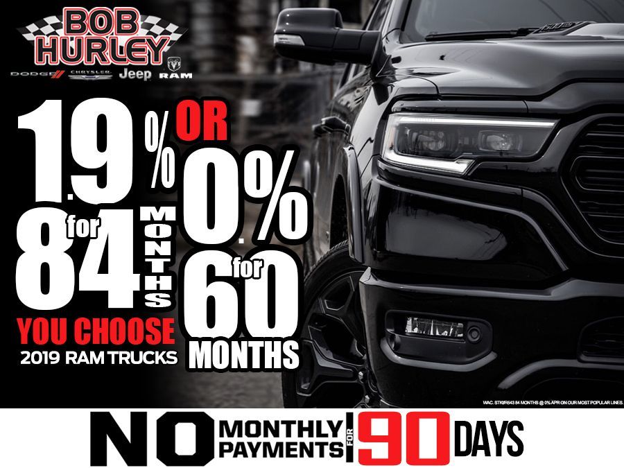 A black ram truck is parked in front of a sign that says `` bob hurley jeep ram ''.