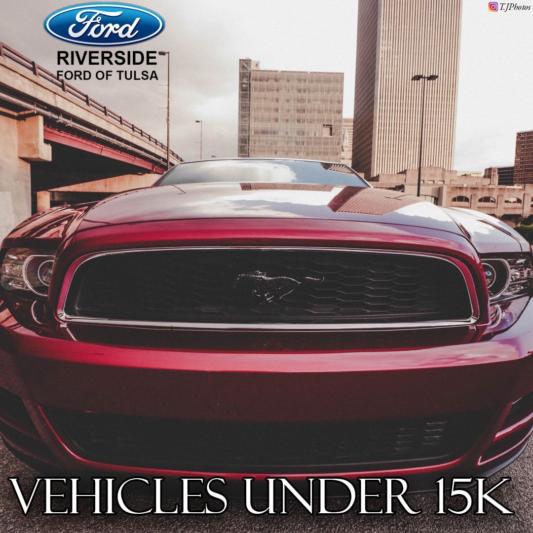 A red ford mustang is parked under a bridge