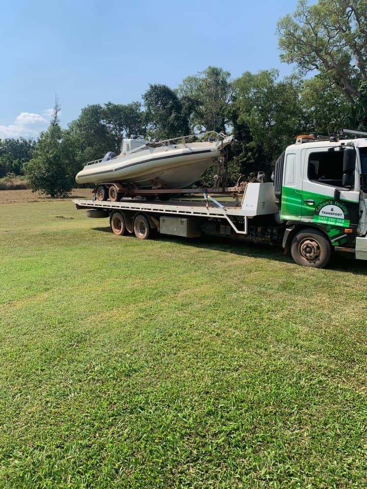 A Tow Truck is Carrying a Boat on a Flatbed Trailer — Cohen’s Towing & 4WD Recoveries In Winnellie, NT