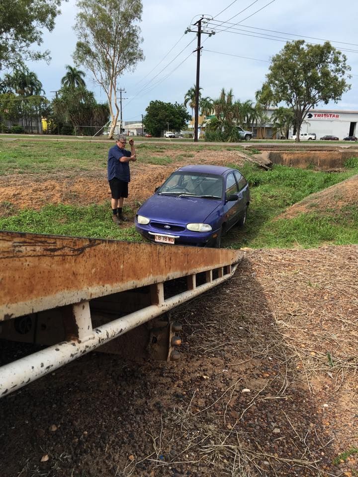A Man is Standing Next to a Blue Car That Has a License Plate  — Cohen’s Towing & 4WD Recoveries In Winnellie, NT