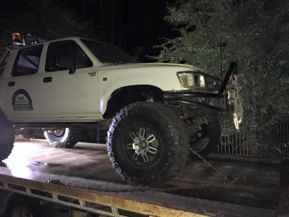 A White Truck is Sitting on Top of a Tow Truck at Night — Cohen’s Towing & 4WD Recoveries In Winnellie, NT