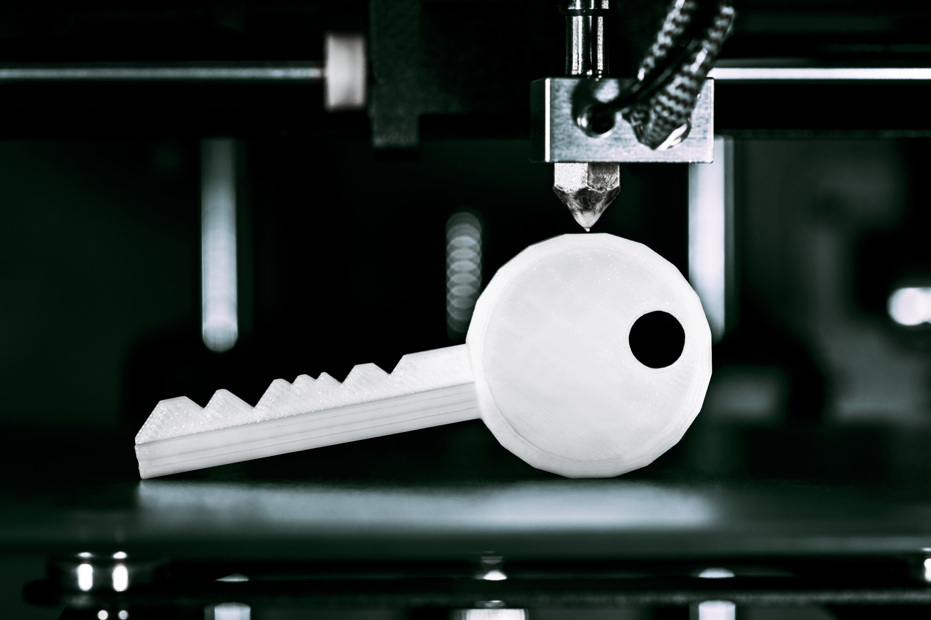 3D printer constructing a white plastic key with a black circular detail.