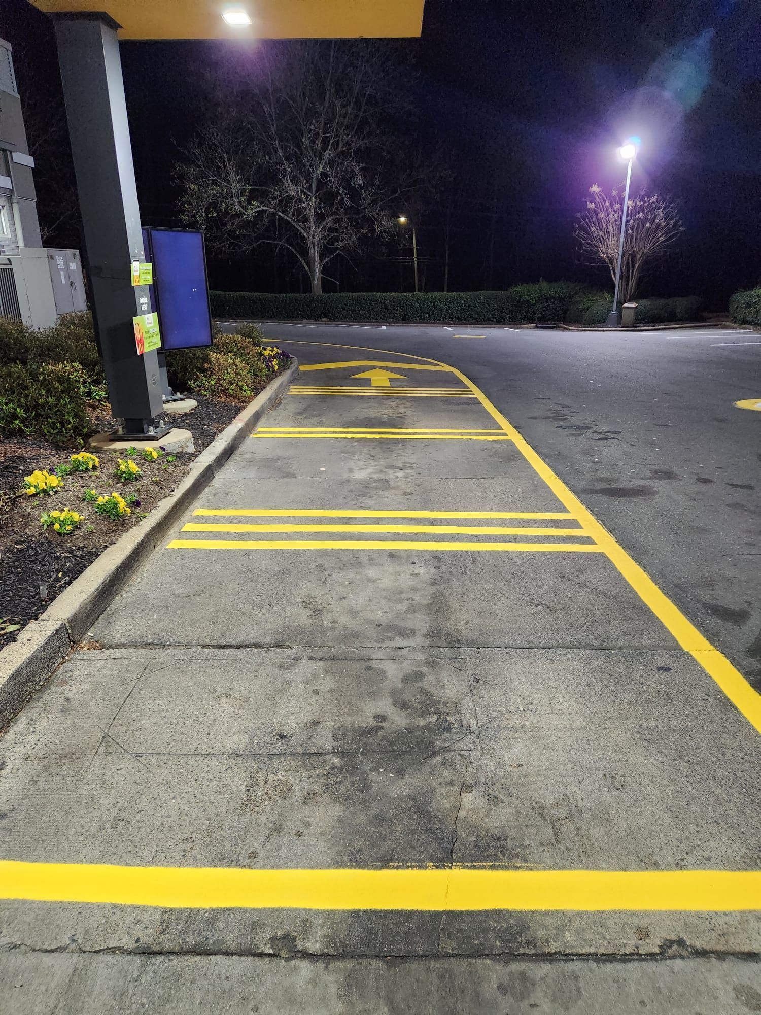 A parking lot with yellow lines painted on it at night.