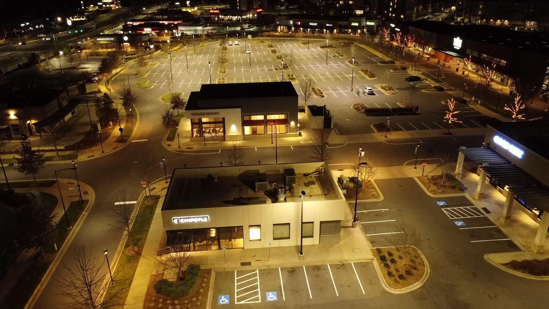 An aerial view of a parking lot at night with a building in the background.