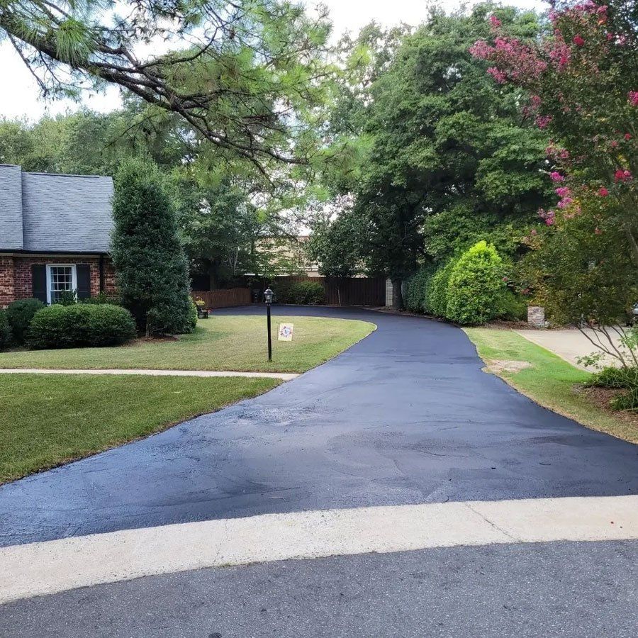 A driveway leading to a house surrounded by trees and grass.