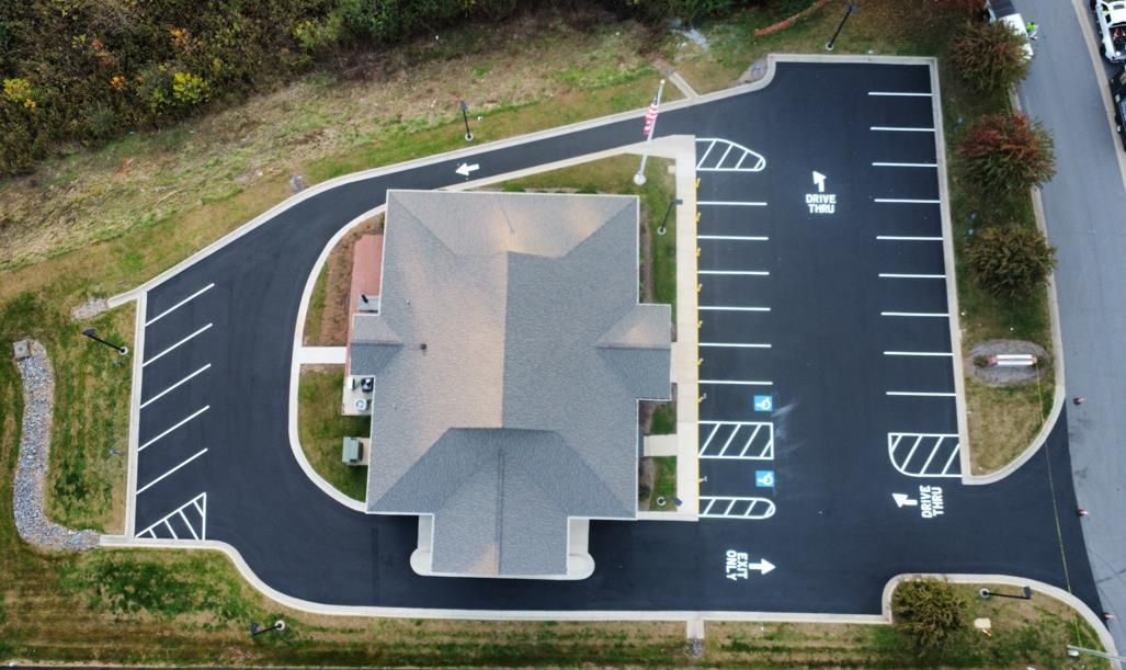 A freshly paved asphalt parking lot lane at night with yellow dashed center lines and overhead lighting.