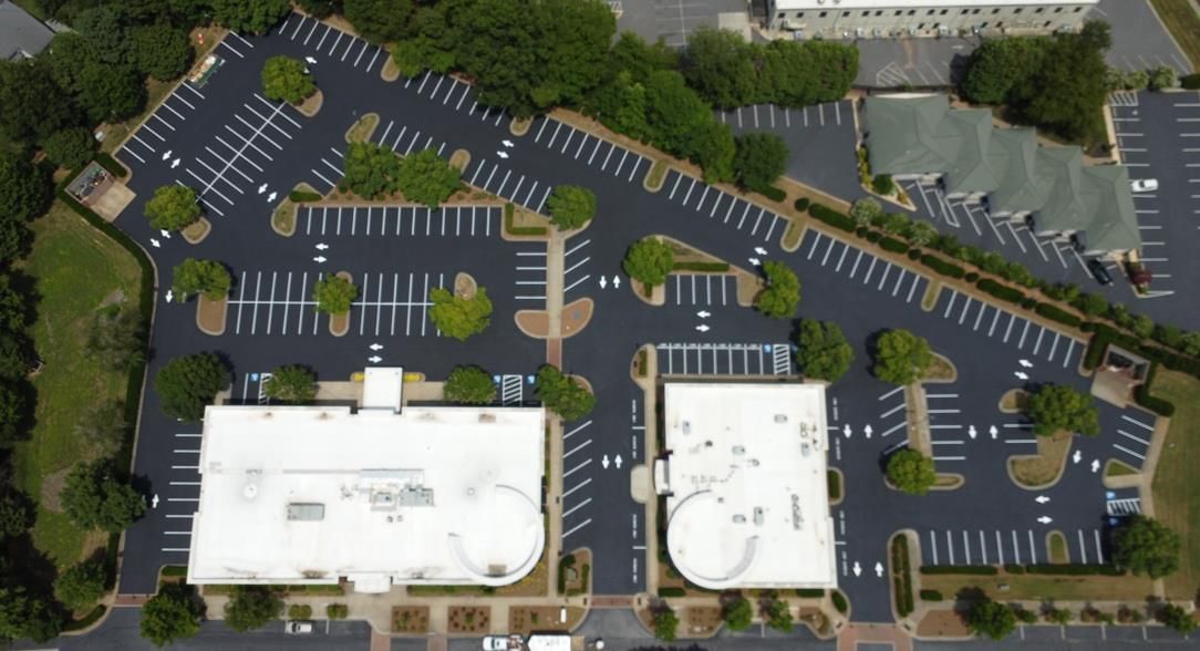 A freshly paved asphalt parking lot lane at night with yellow dashed center lines and overhead lighting.