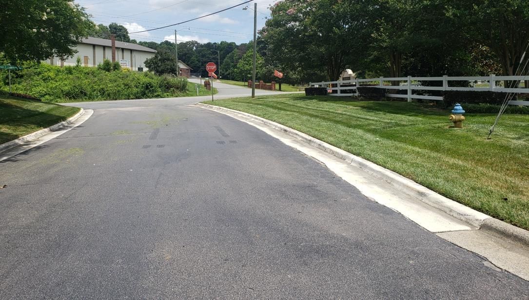 A motorcycle rider practices maneuvering around orange traffic cones in a large, paved parking lot.