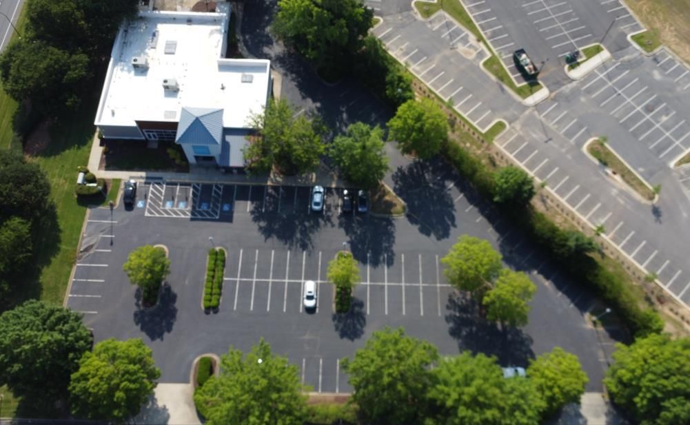 A motorcycle rider practices maneuvering around orange traffic cones in a large, paved parking lot.