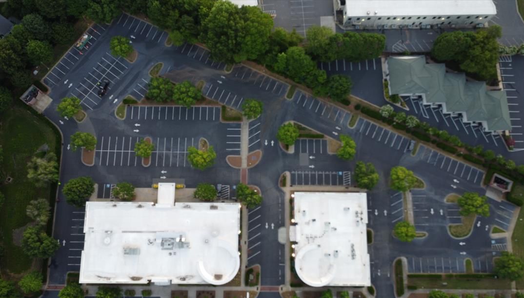 A freshly paved asphalt road at night, with a Lowe's store and parking lot illuminated in the background.